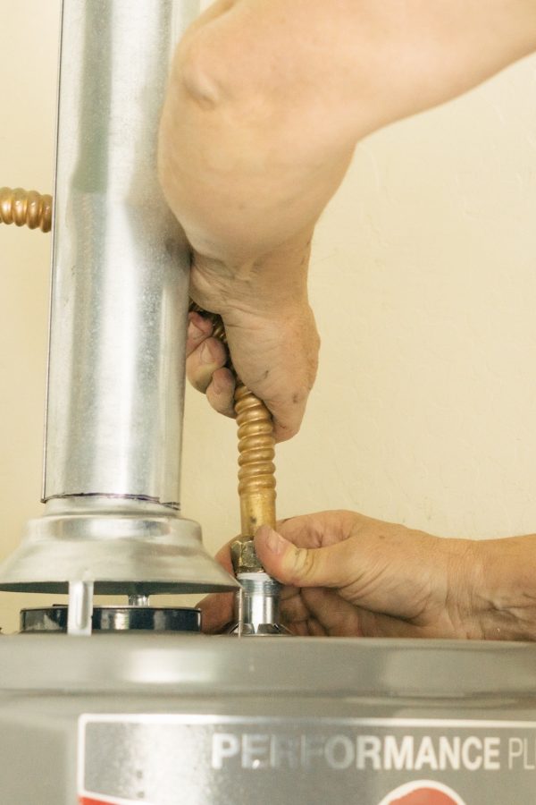 Adult male hands on water line going into a hot water heater Adult male hands on water line going into a hot water heater