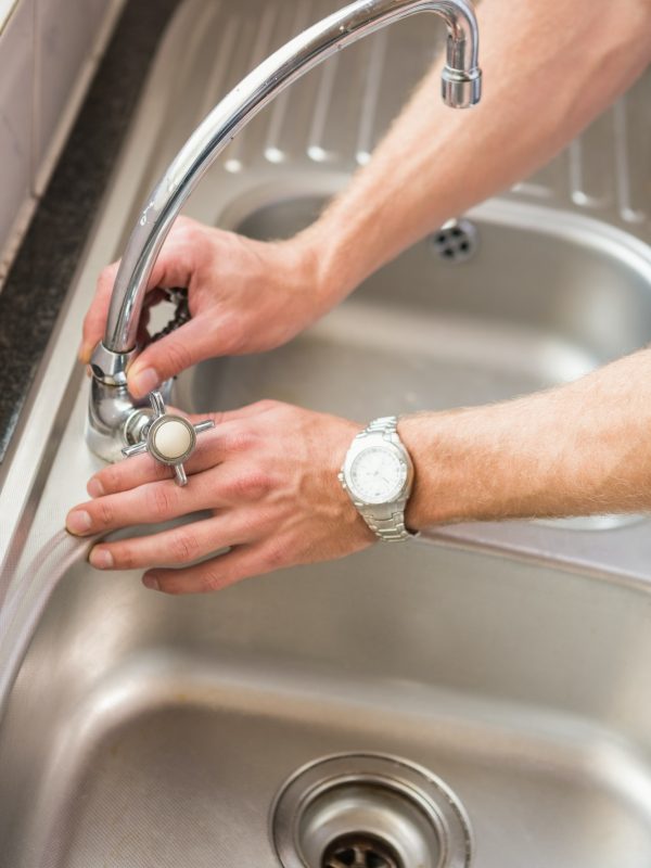 Man fixing tap with pliers at home in the kitchen Man fixing tap with pliers at home in the kitchen